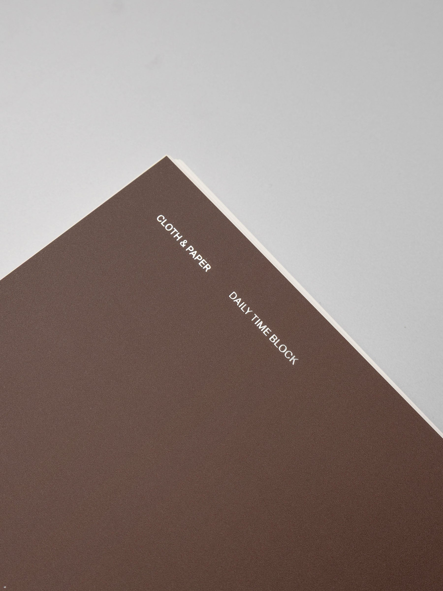 Spiral Notebook in size A5 and color Espresso brown with Daily Time Block interior pages shown close up to display foil details on soft touch cover.