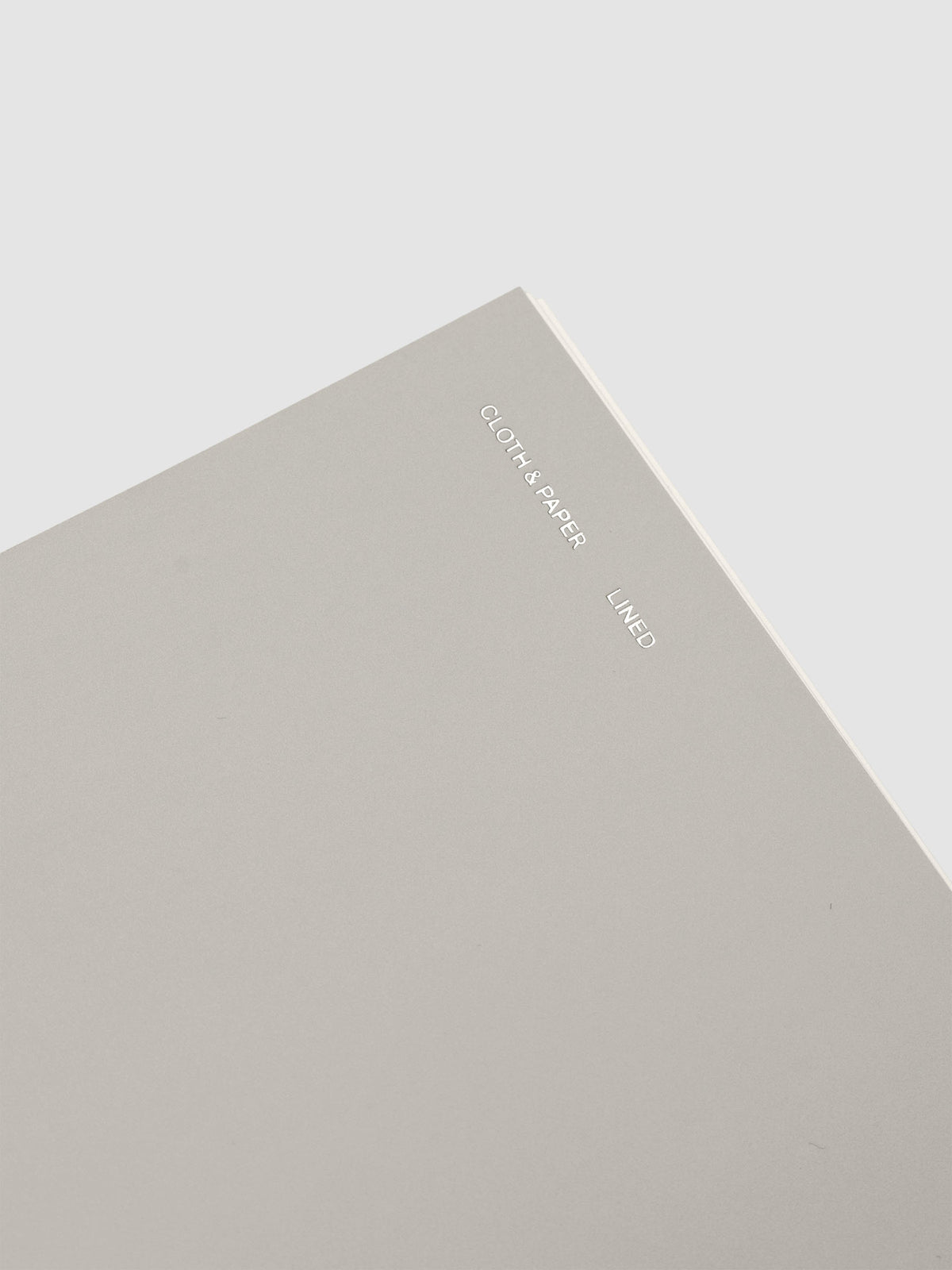 Spiral Notebook in size CP Petite and color Ash with Lined Notes interior pages showing a close up of the foil details on the soft touch dashboard.