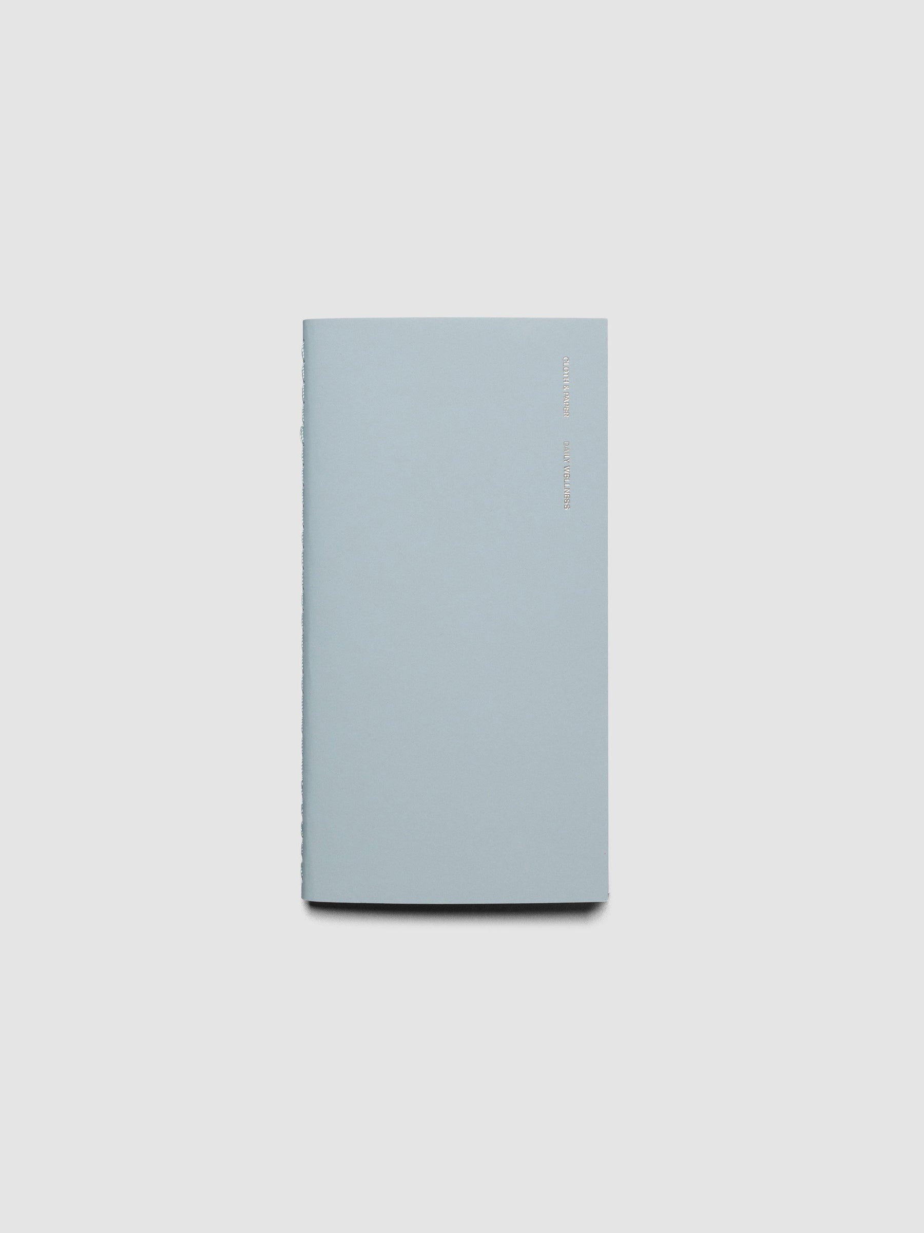 Travel Notebook in size Pocket Plus in color Smoked Salt (blue) with Daily Wellness pages shown closed.