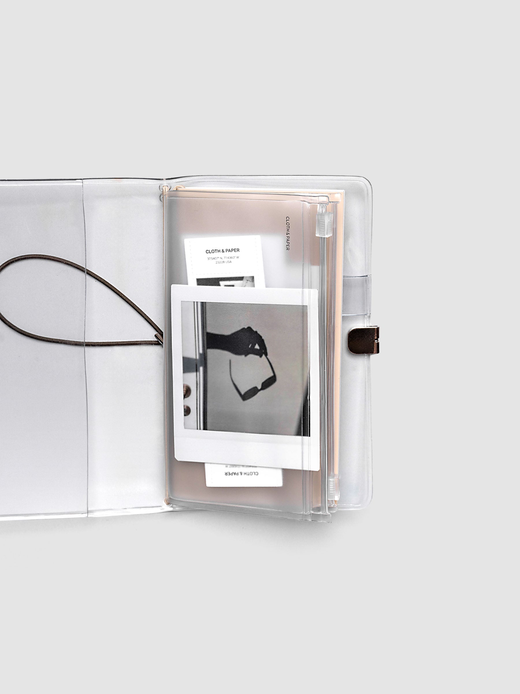 Pocket Plus travel notebook storage holder with stickers and cards inside, slipped into a clear vinyl travel notebook cover