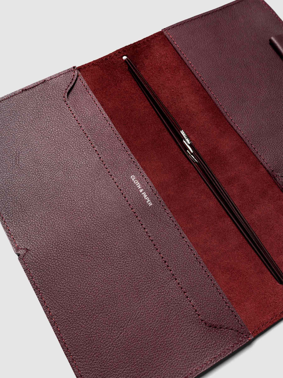 Deep red leather travel notebook cover in size A5 Slim shown open with interior pockes and elastic bands.