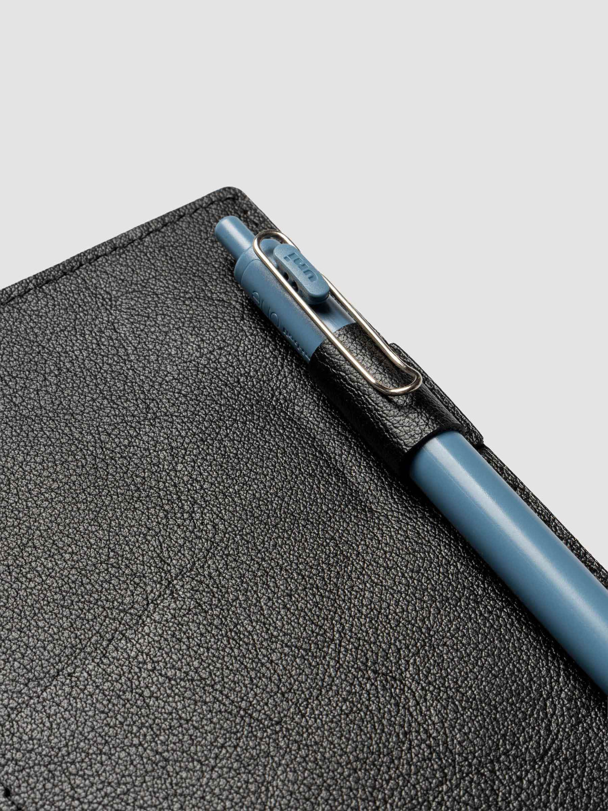 Black leather travel notebook cover in size A5 Slim shown open with a pen in the pen loop.