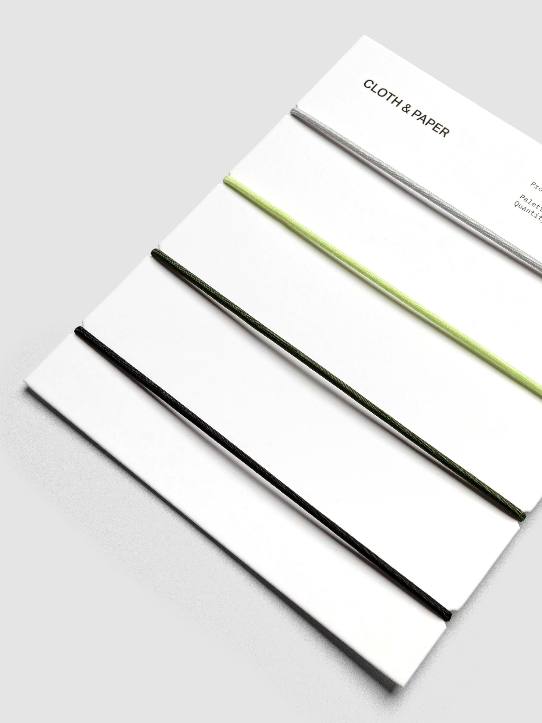 Packaging close-up showing orange, grey, green, and black elastic bands.