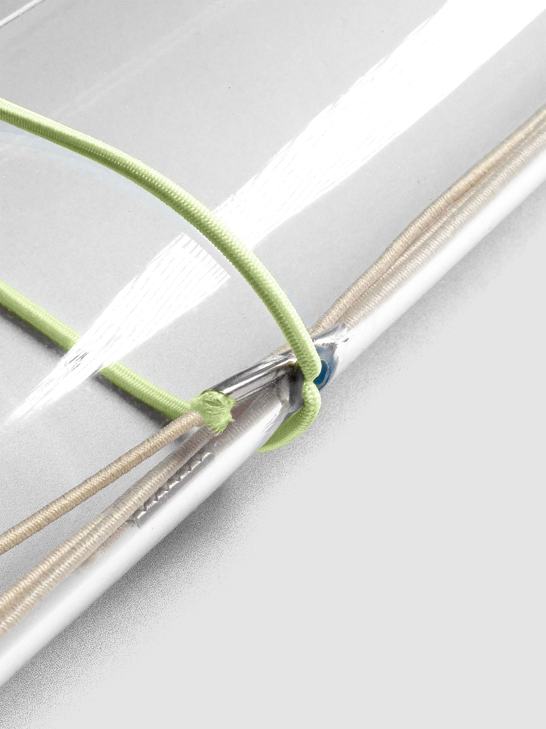 Light green elastic exterior band looped through clear vinyl travel cover spine.