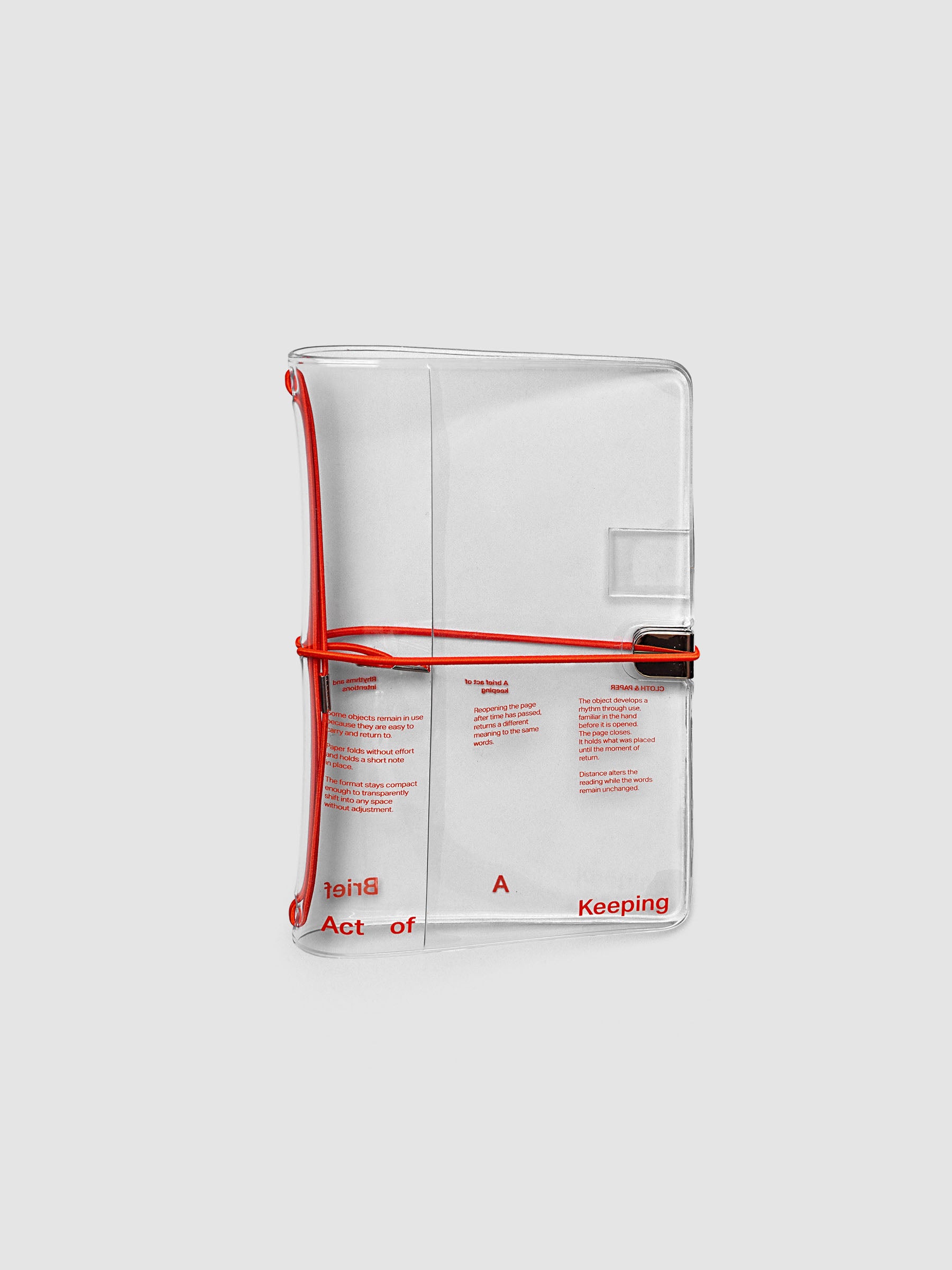 Act of Keeping Travel Notebook Cover in Pocket Plus size, closed, in clear vinyl with deep orange typographic print and metal tab closure