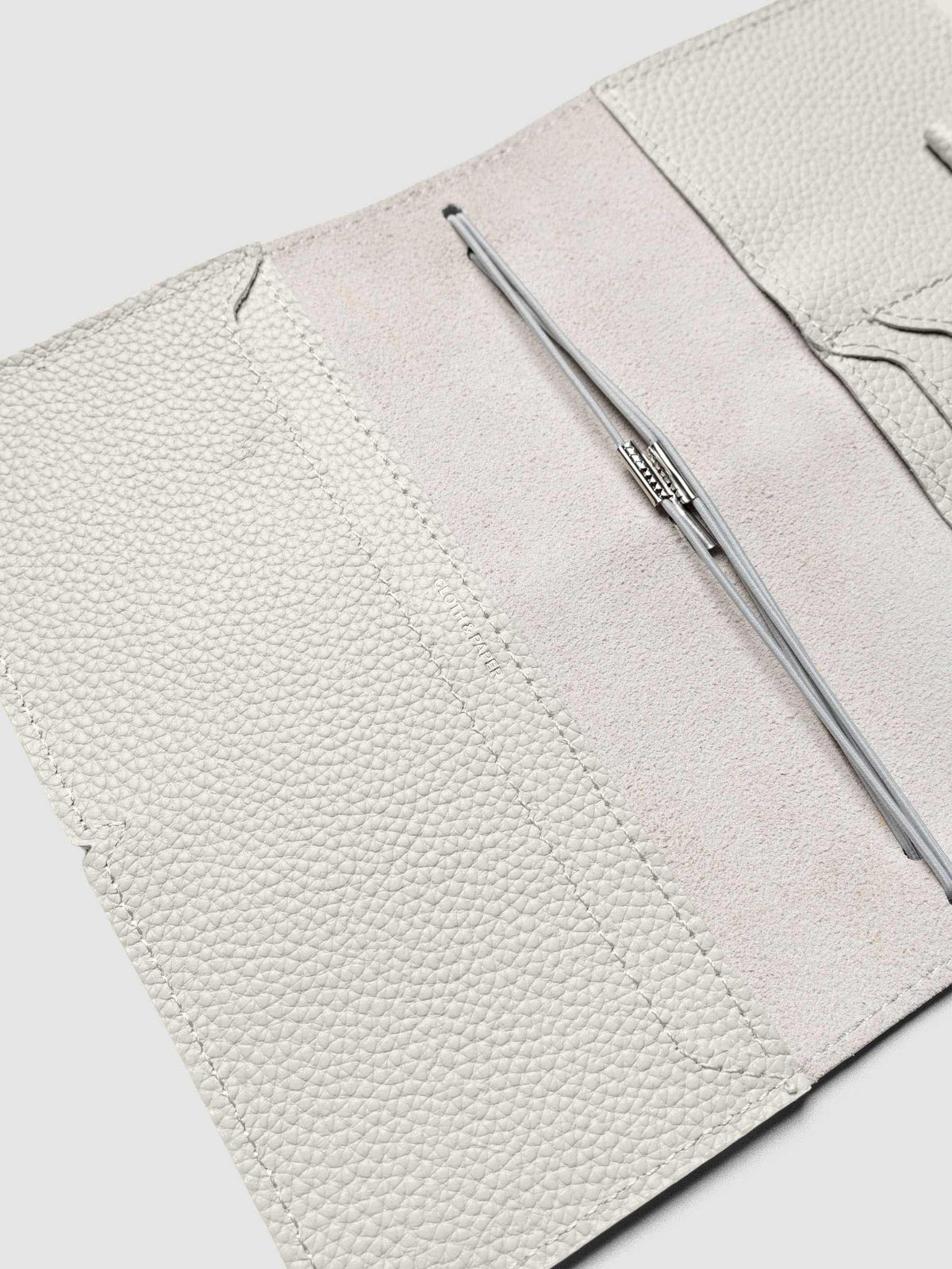 Light grey leather travel notebook cover in size Pocket Plus shown open with interior pockes and elastic bands.