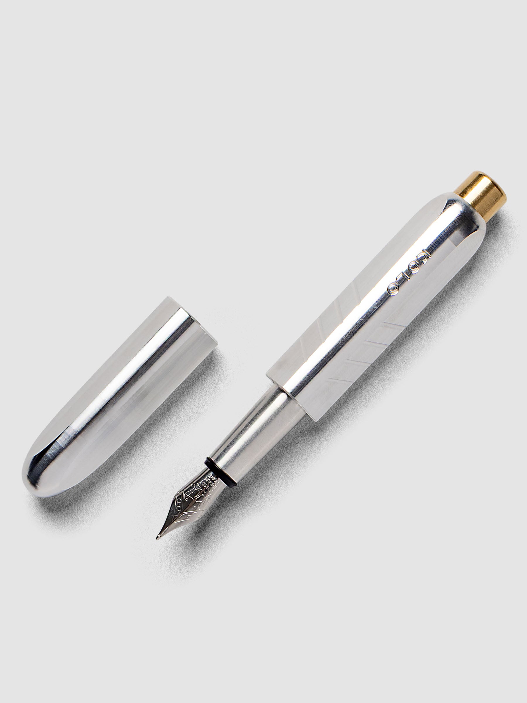 Kolo Tino Fountain Pen in the color Raw Aluminum, a silver toned metal barrel with brass accents and a silver medium nib shown with cap off.