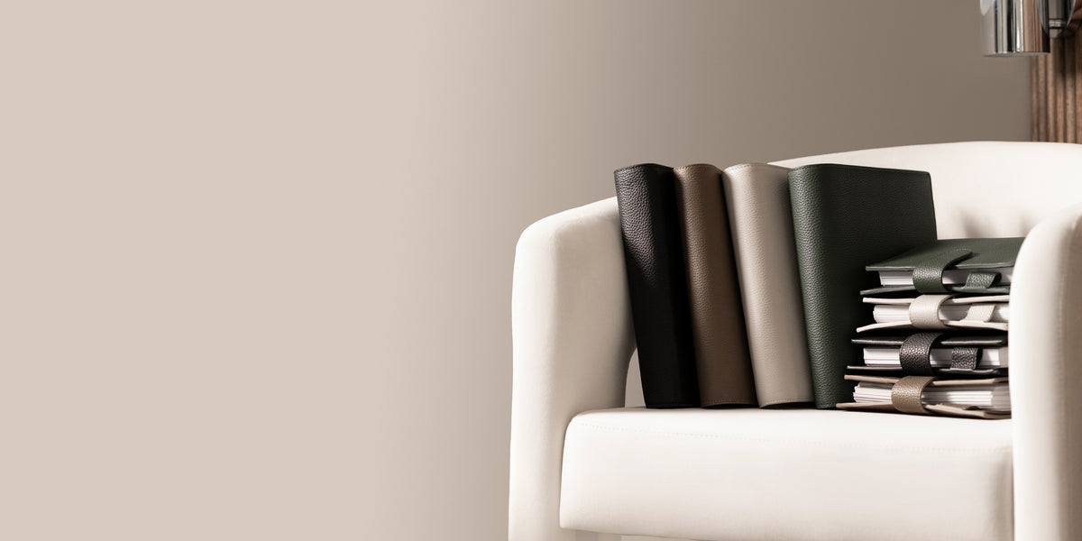 Several Foundations 6-Ring Leather Agendas are sitting on a white chair against  light brown background.