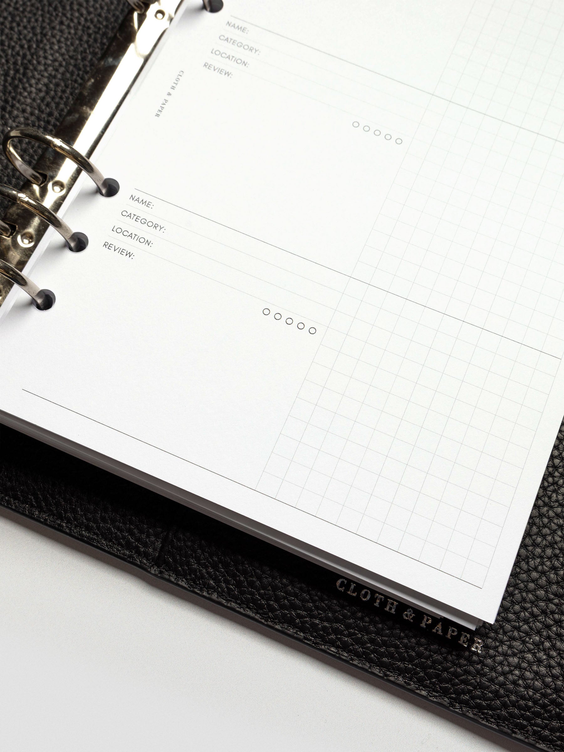 Detail shot of the insert’s layout inside the binder, showing two tracker blocks and a visible Cloth & Paper logo on the agenda cover.