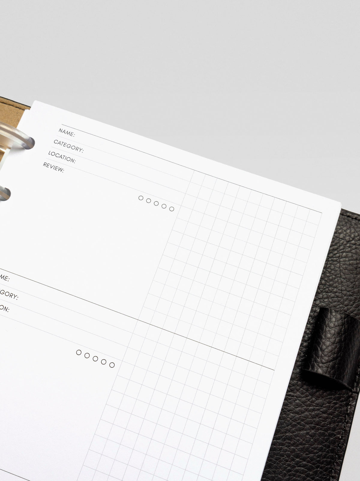 Close-up of the top portion of a Half Letter Experience Tracker Insert showing blank fields and grid space. The clean, minimal design is visible with soft lighting and leather planner edge.