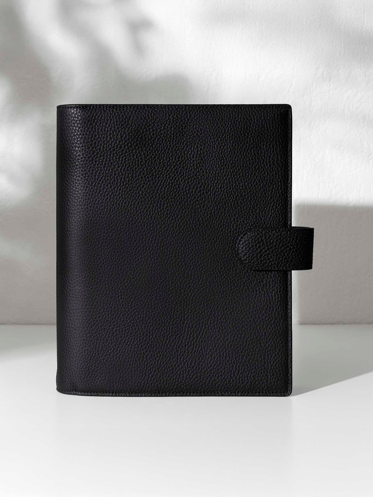 Black leather agenda displayed against a shadowed background.