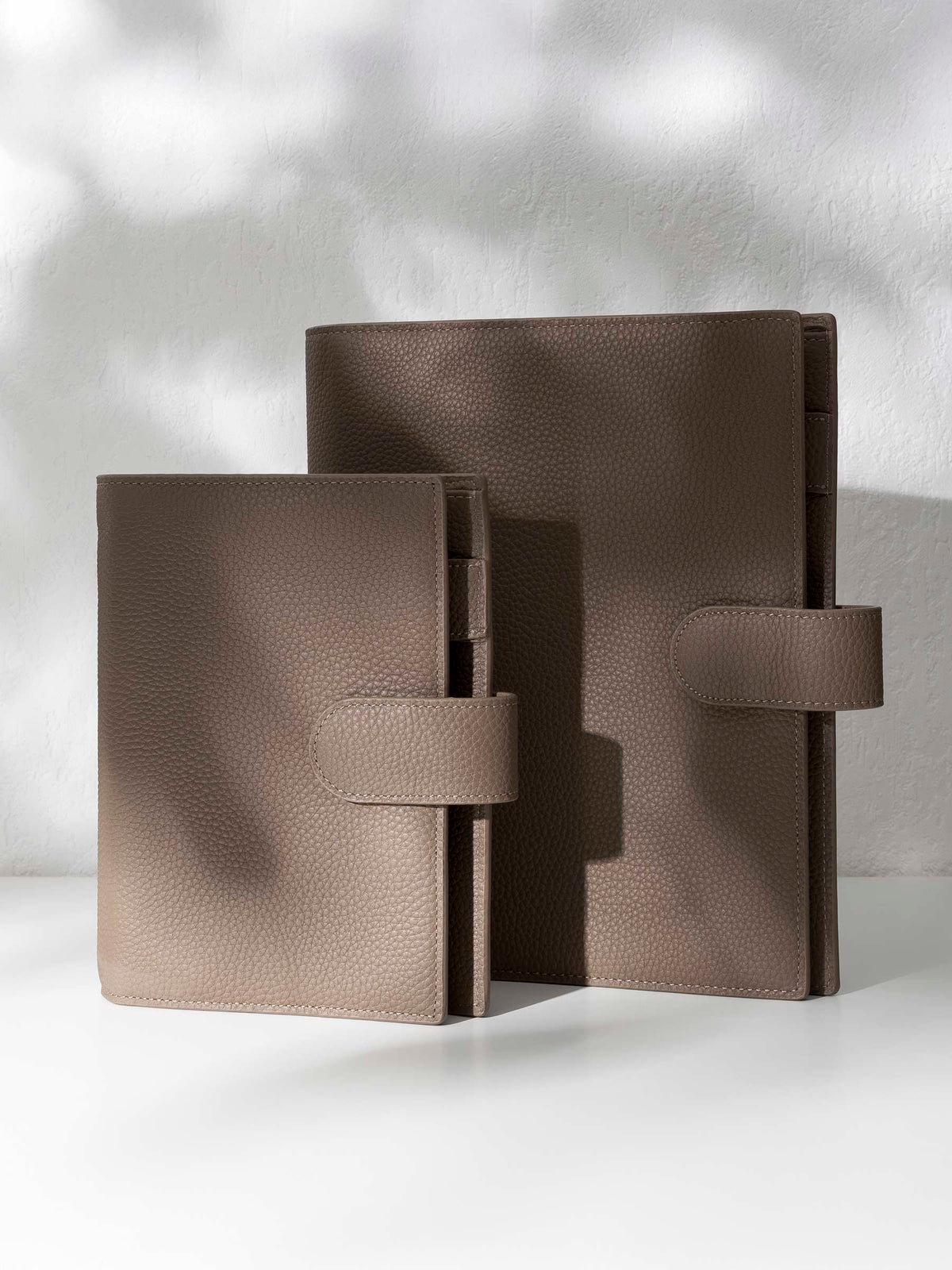 Two brown leather agendas displayed against a shadowed background.