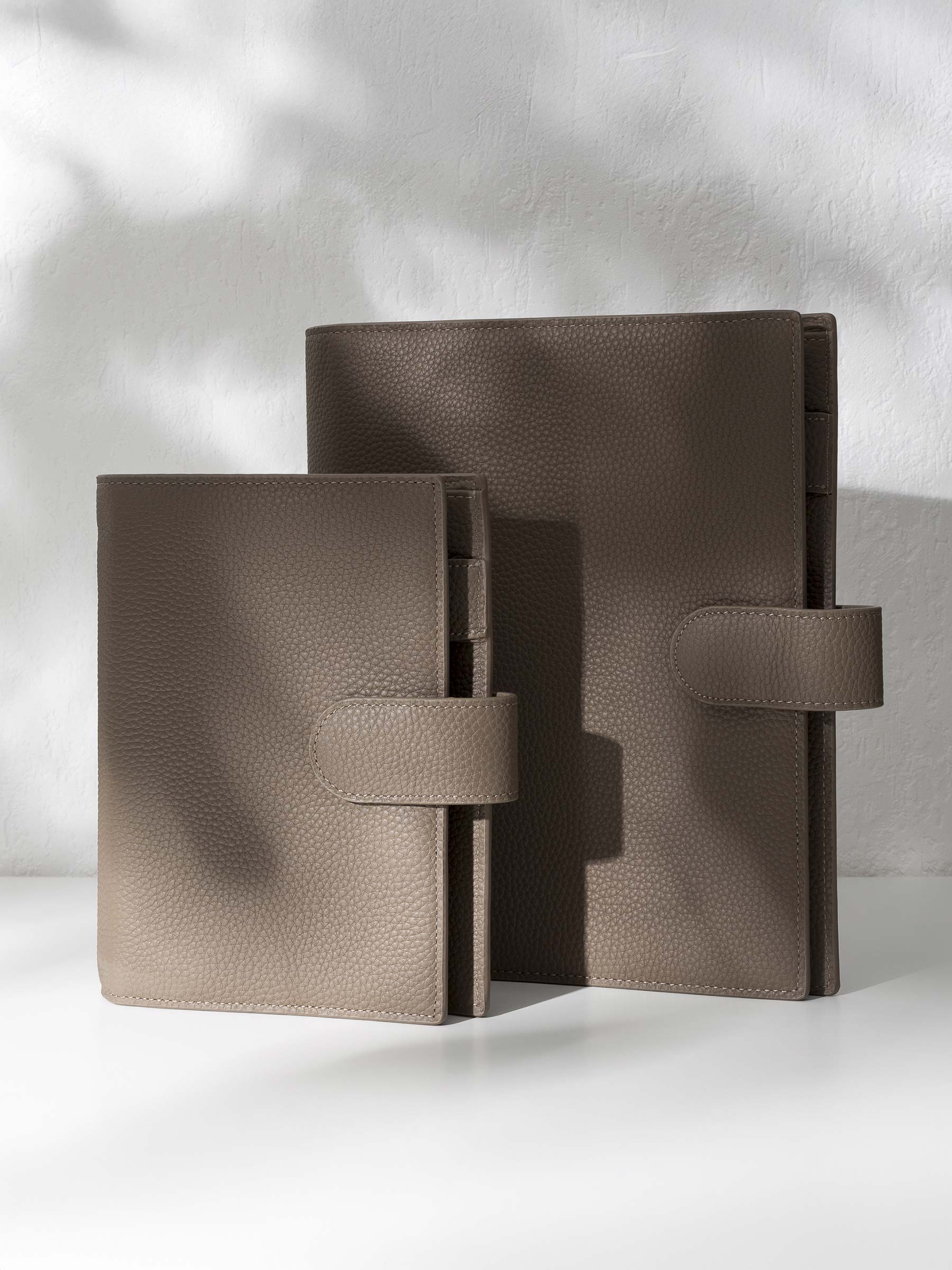 Two brown leather agendas displayed displayed against a shadowed background.
