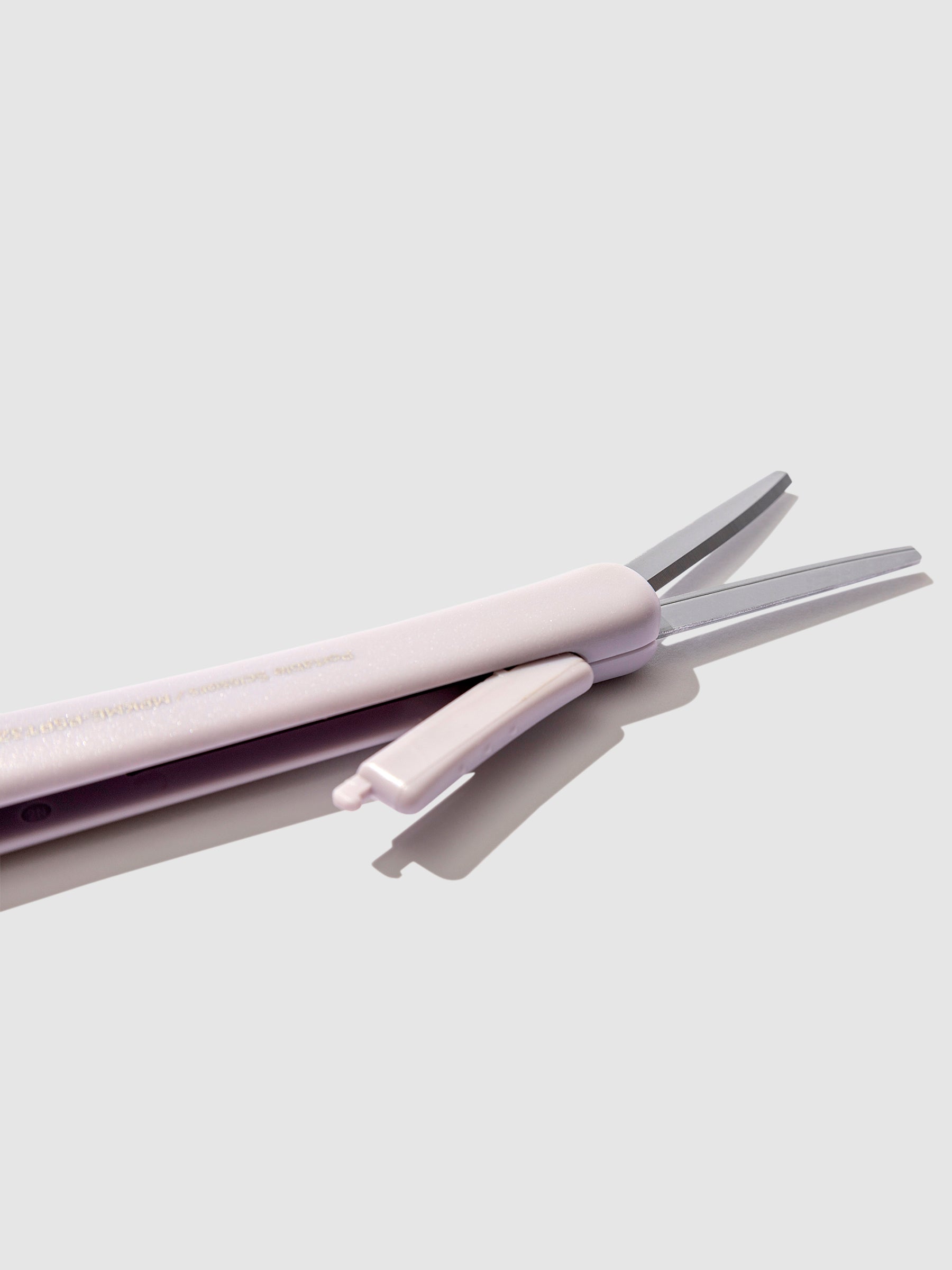 Closeup of scissors with blade exposed, showing the mechanism that exposes the scissor blades. Color shown is Misty Lilac. 