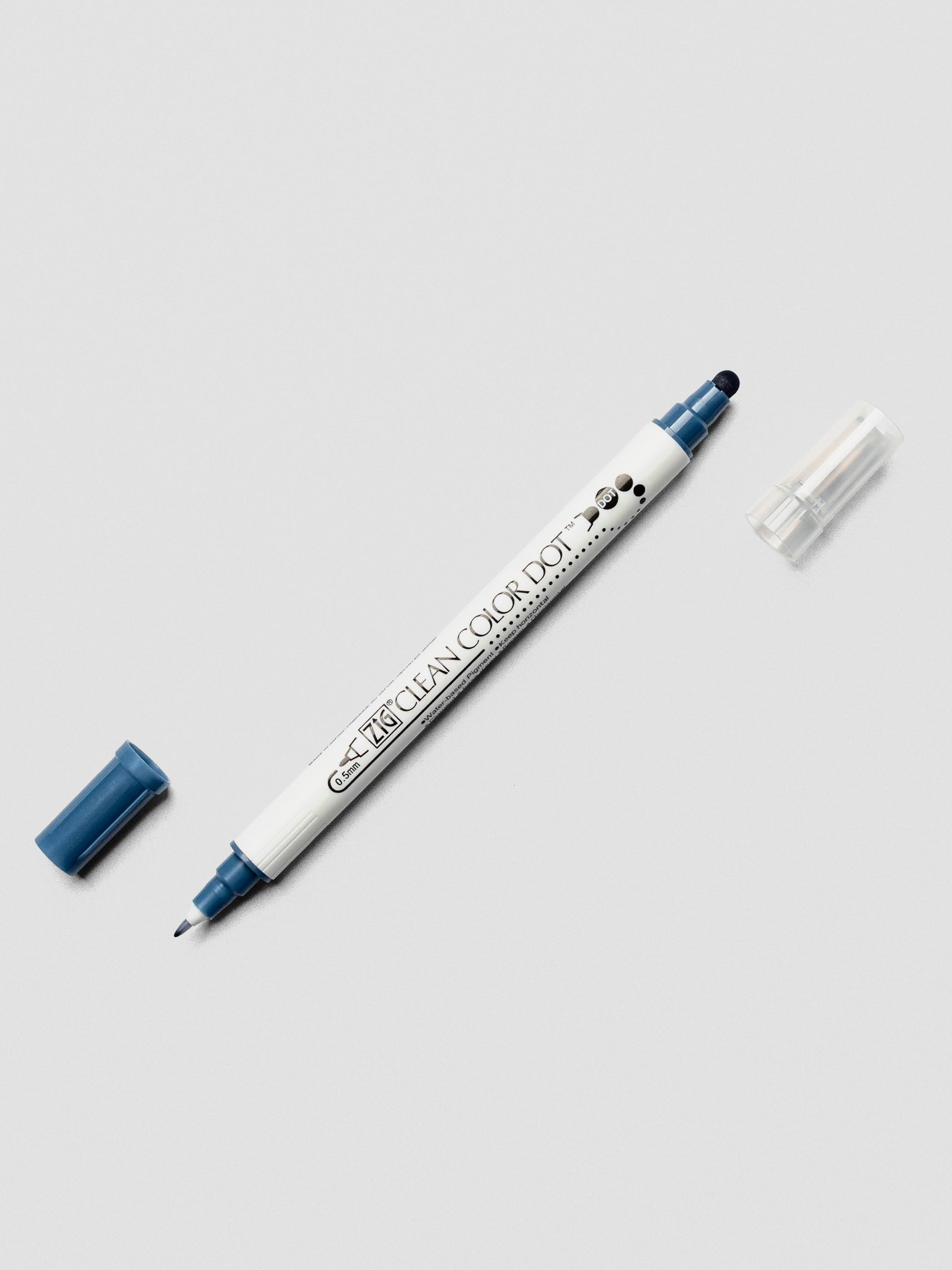 Kuretake ZIG Clean Color Dot Dual Tip Marker in Denim with both caps removed, showcasing the twin-tip design on a light surface.