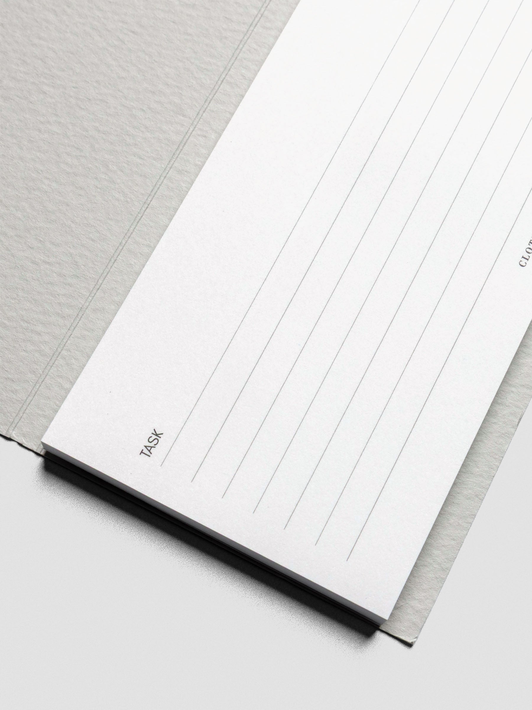 Angled close-up of the lower portion of the sticky note, showing crisp horizontal lines under the “Task” heading and the thickness of the notepad sheets.