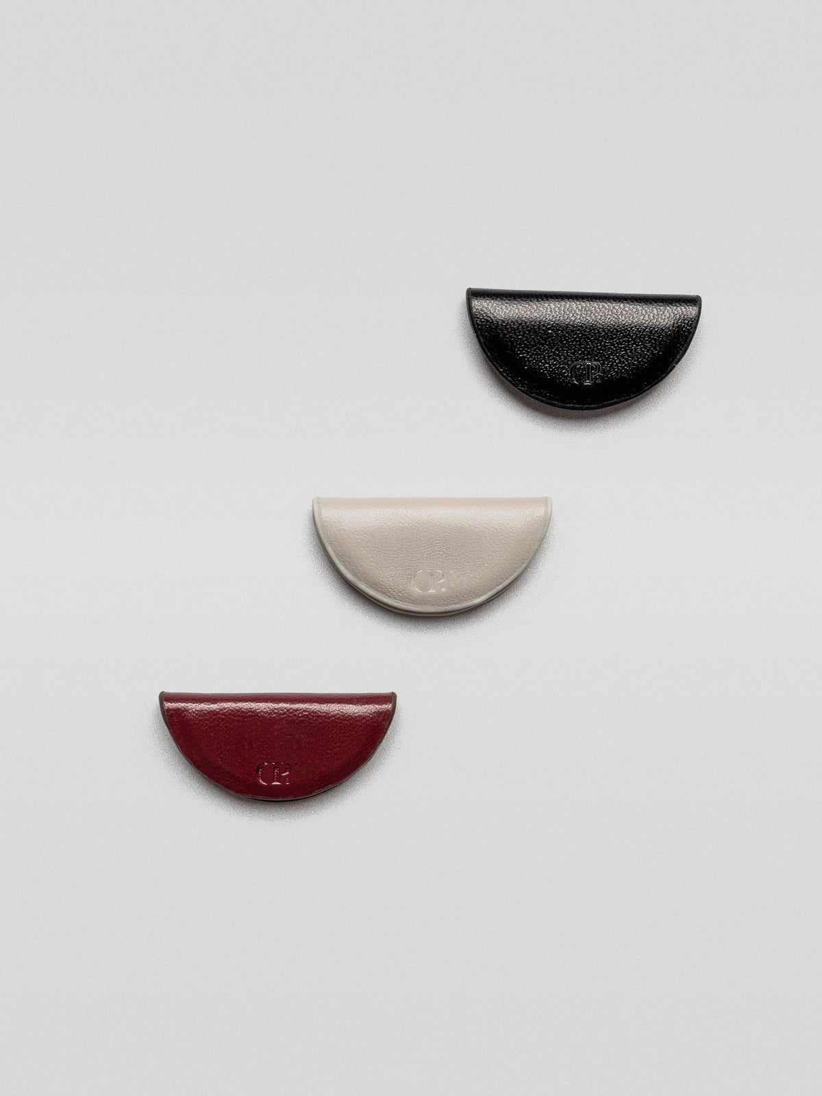 Three magnetic leather bookmarks from the Mini eCLIPse Set | Vol. 2 laid out individually on a flat surface, showing black, cream, and burgundy colors.