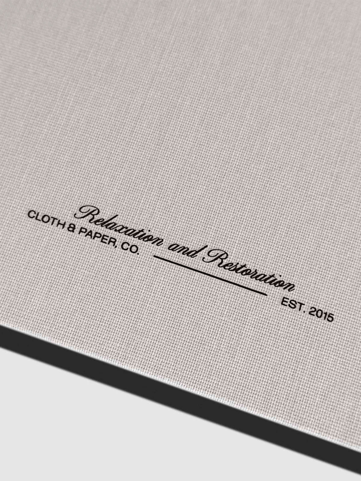 Closeup of fabric detailing and Rilassati tagline printed on folio. Text reads "Relaxation and Restoration / Cloth & Paper Co. / Est. 2015"