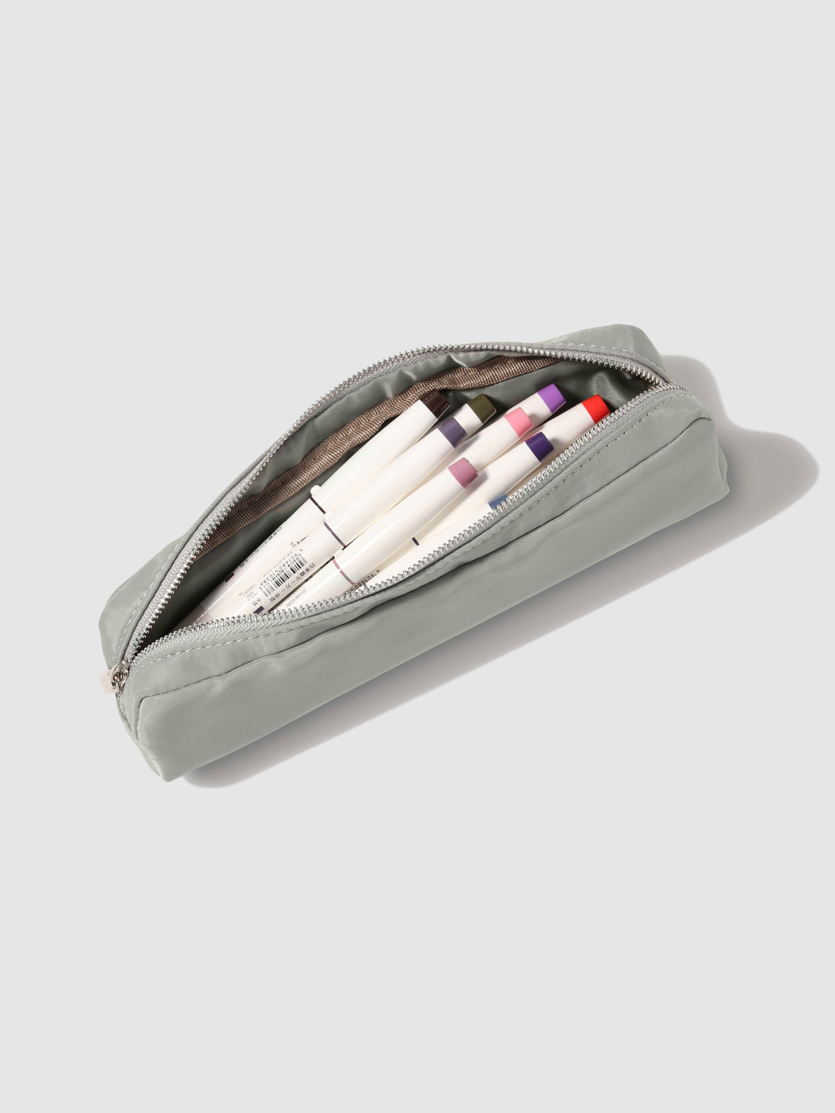 Ristretto pencil pouch displayed open on a neutral background. A collection of pens are inside the pouch. 