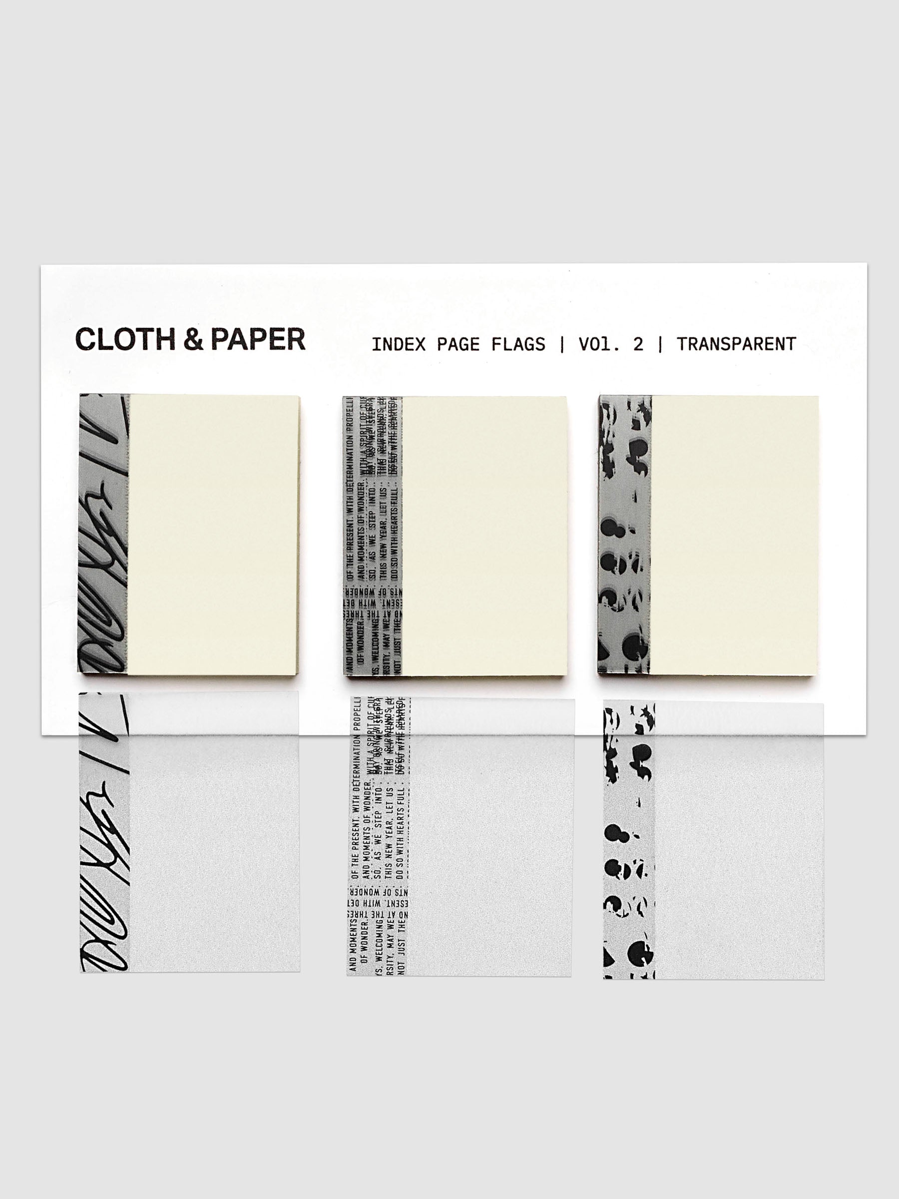 A set of transparent index page flags from Cloth & Paper, Volume 2, shown in a clean studio layout. The flags feature various black and gray abstract patterns and text designs on a clear, semi-transparent base, displayed against a light gray background.