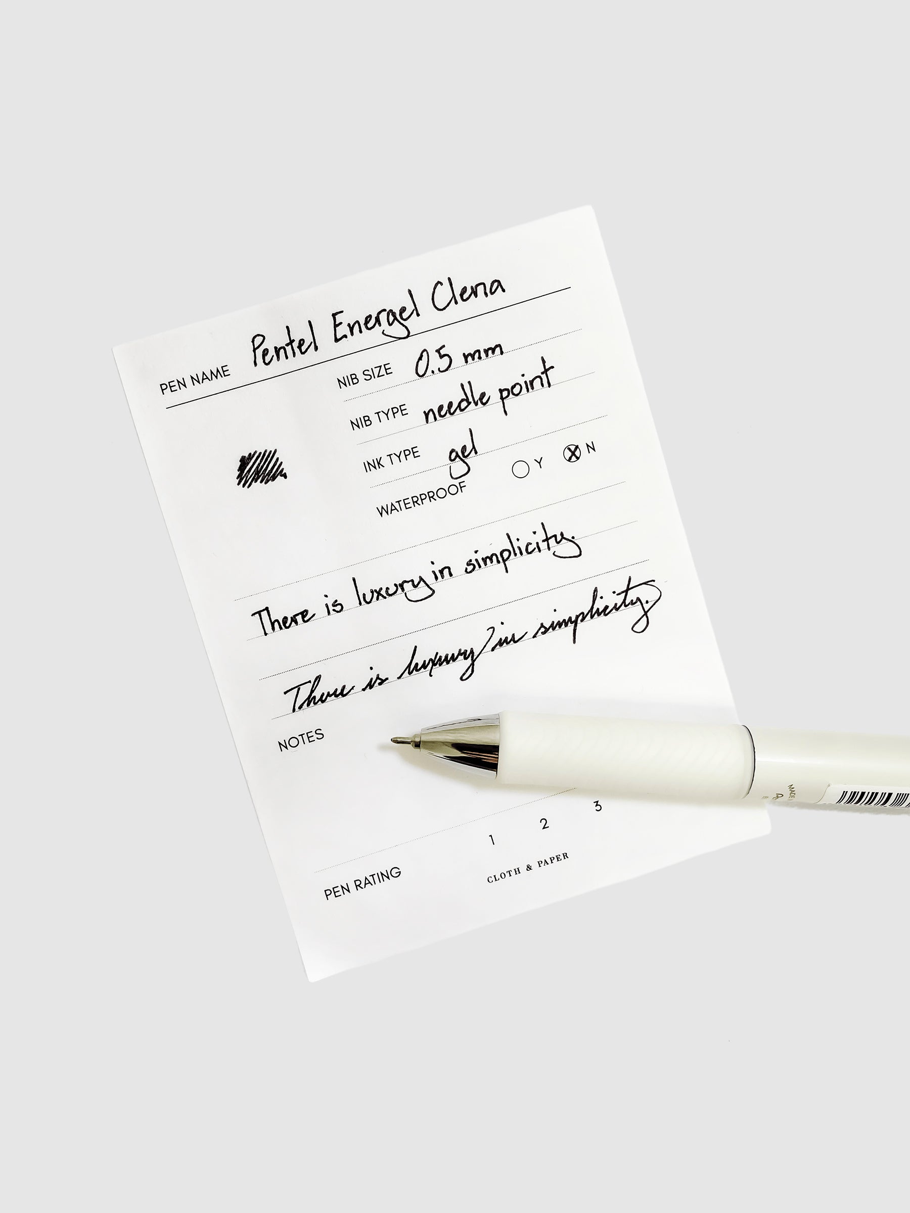 Pentel EnerGel Clena Pen. Cloth and Paper. Pen resting on pen test sheet displaying writing sample.