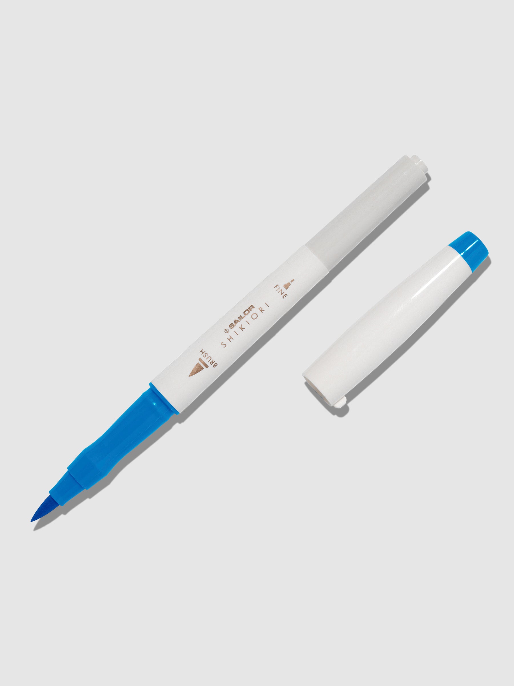 Brush pen displayed on a neutral background. It is uncapped with its brush nib exposed, and the cap lying parallel to the marker. Color pictured is Souten. 
