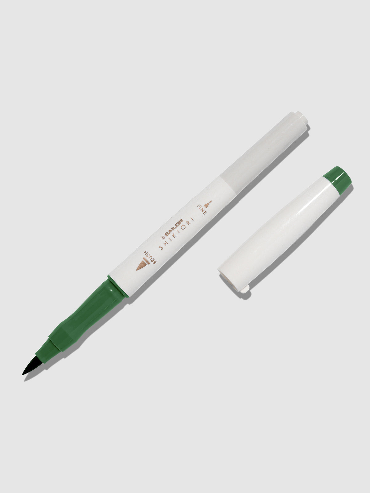 Brush pen displayed on a neutral background. It is uncapped with its brush nib exposed, and the cap lying parallel to the marker. Color pictured is Tokiwamatsu. 
