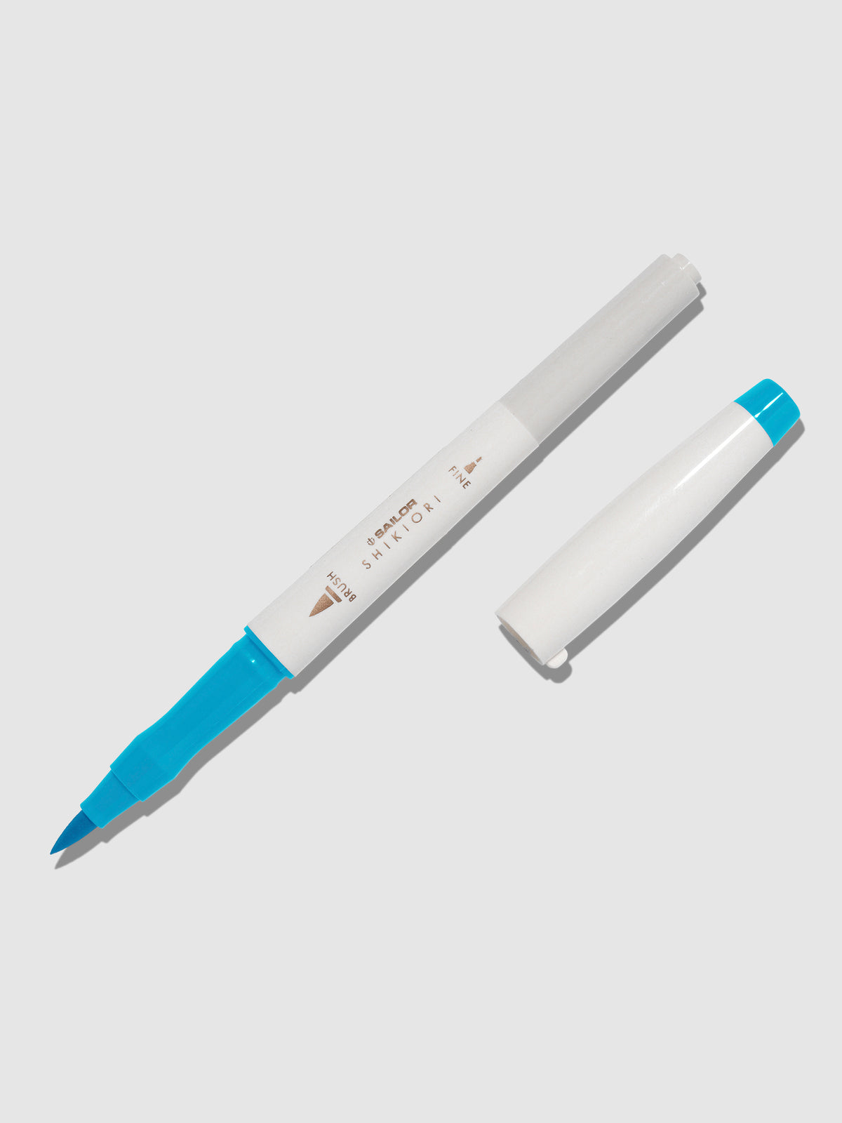 Brush pen displayed on a neutral background. It is uncapped with its brush nib exposed, and the cap lying parallel to the marker. Color pictured is Yukiakari. 