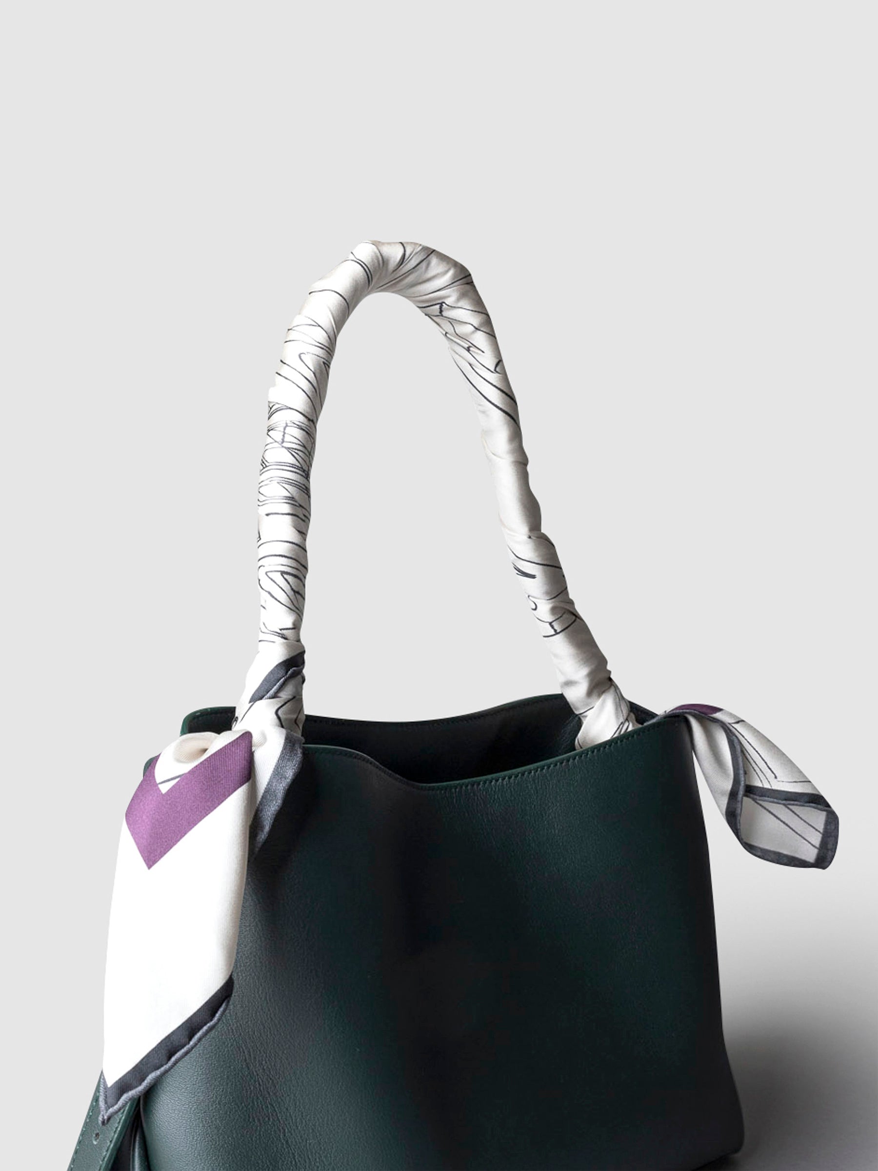 Scarf shown tied around the handle of a Valencia leather handbag.