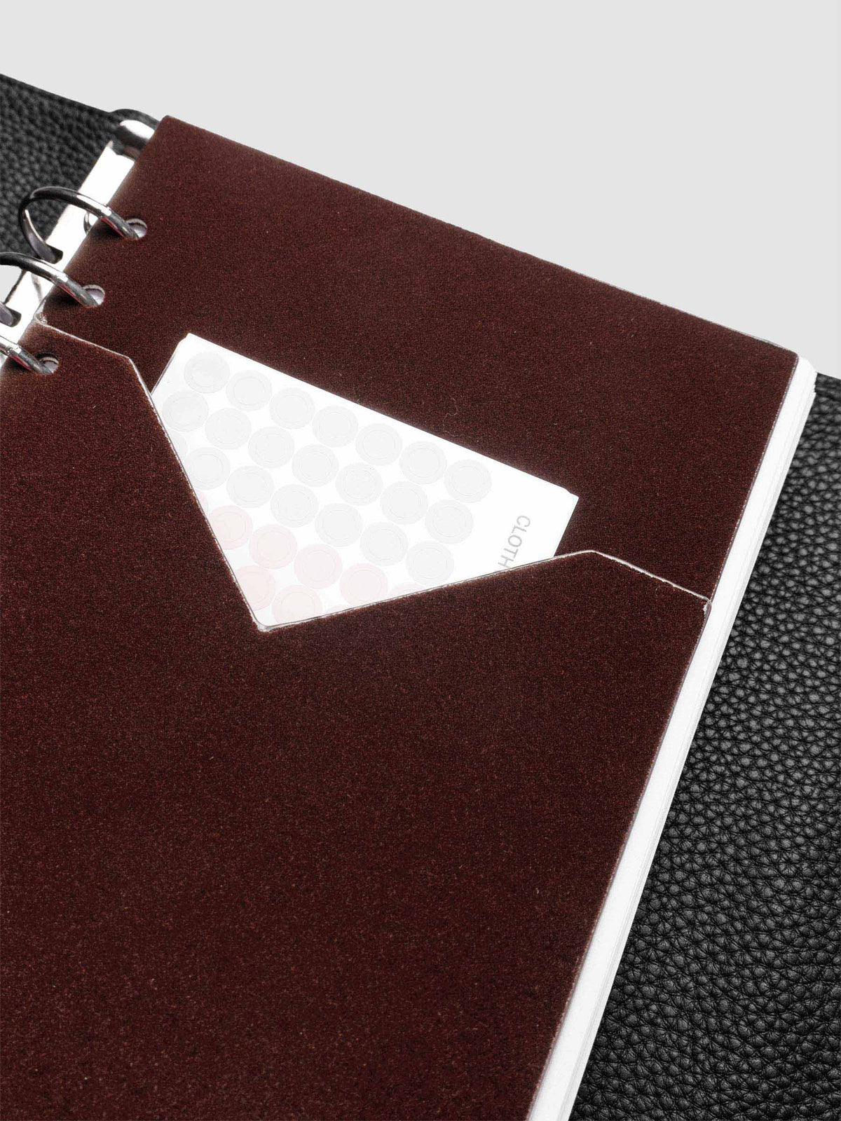 Velvet Pocket Folder in Bordeaux pre-punched for A5 planners shown in a black leather agenda with stickers inside the pocket.