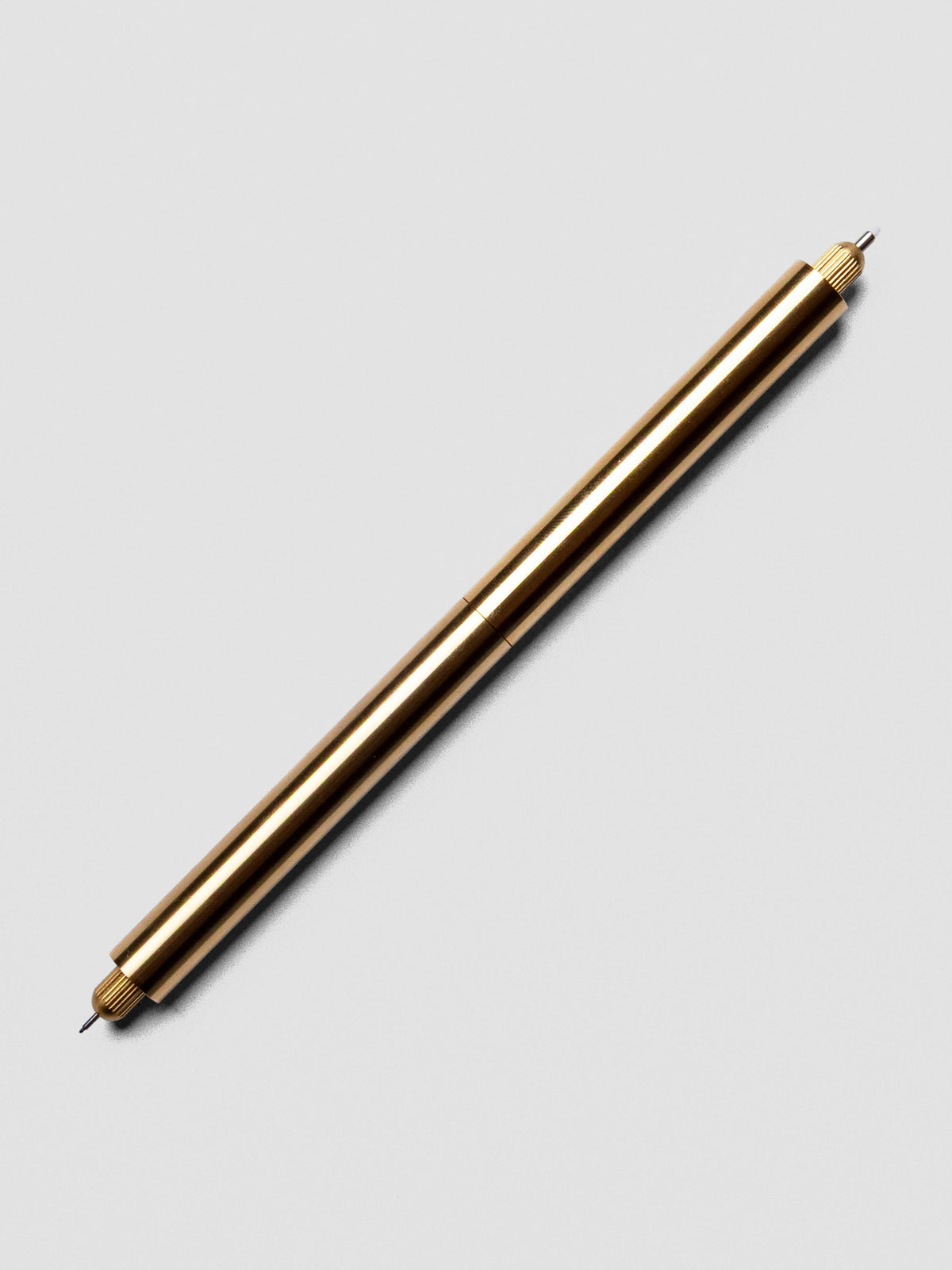Close-up of Brass Lumos Pro Duo Tip Pen angled across a notebook page, uncapped on both ends.
