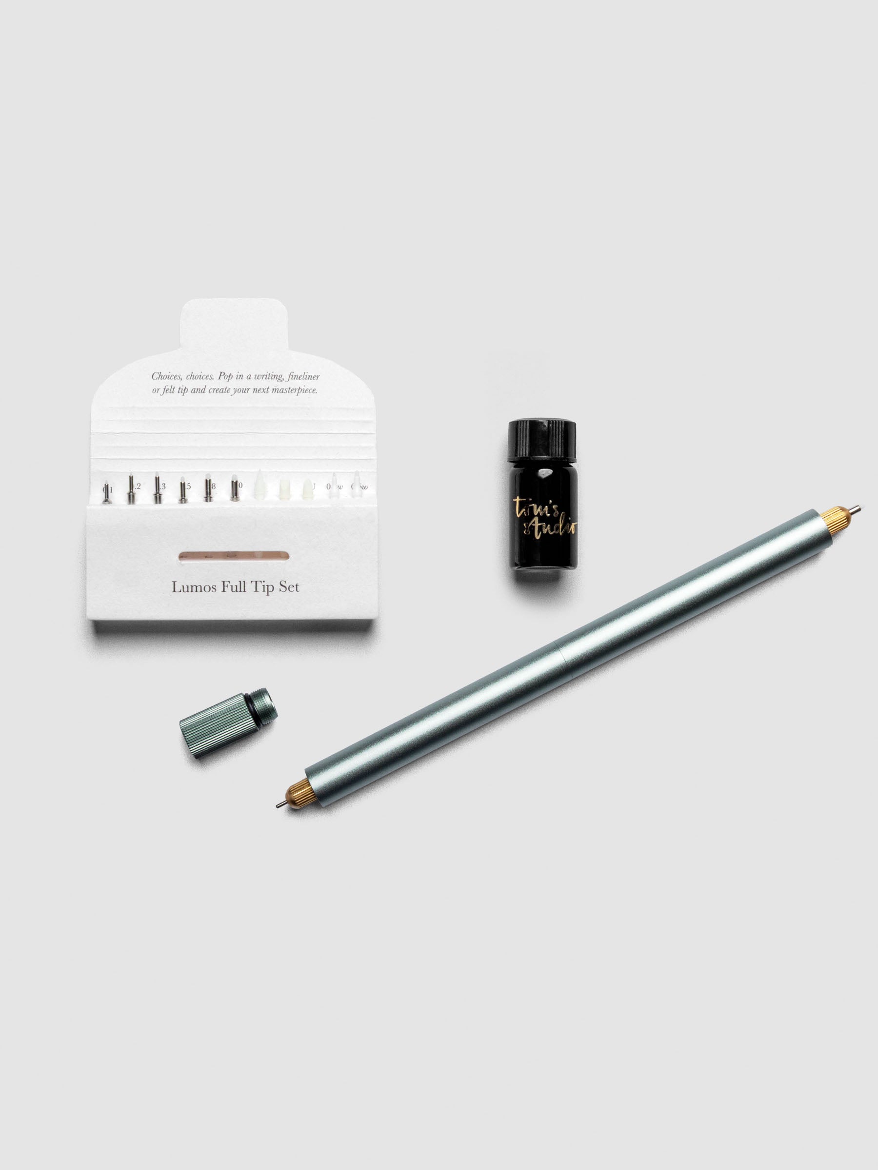Sage Green Lumos Pro Duo Tip Pen resting diagonally on an open notebook, uncapped, shown with tips set and ink.