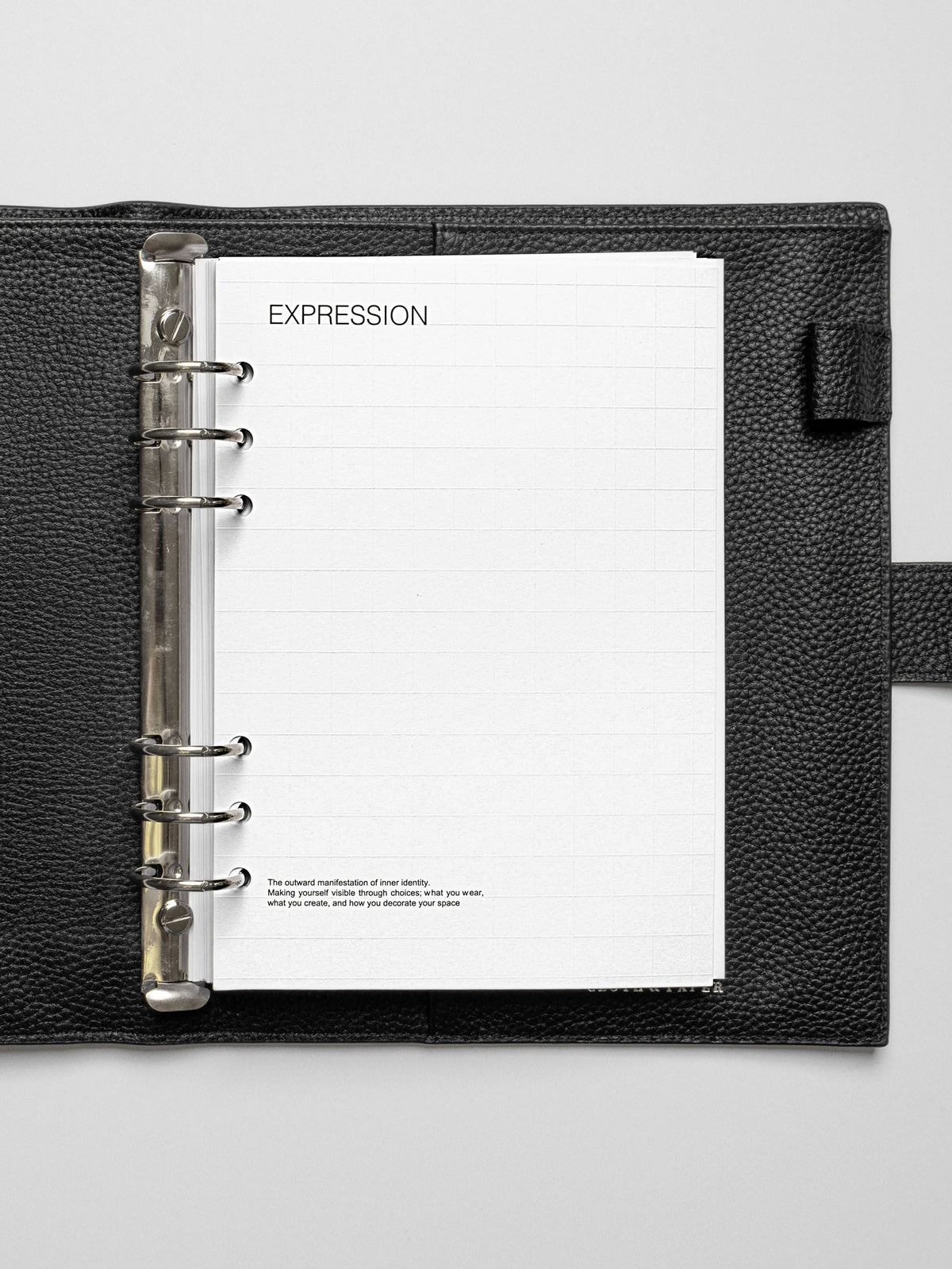An A5 Tile Planner Dashboard featuring a grid layout with the word "EXPRESSION" at the top, placed in a black leather 6-ring planner.