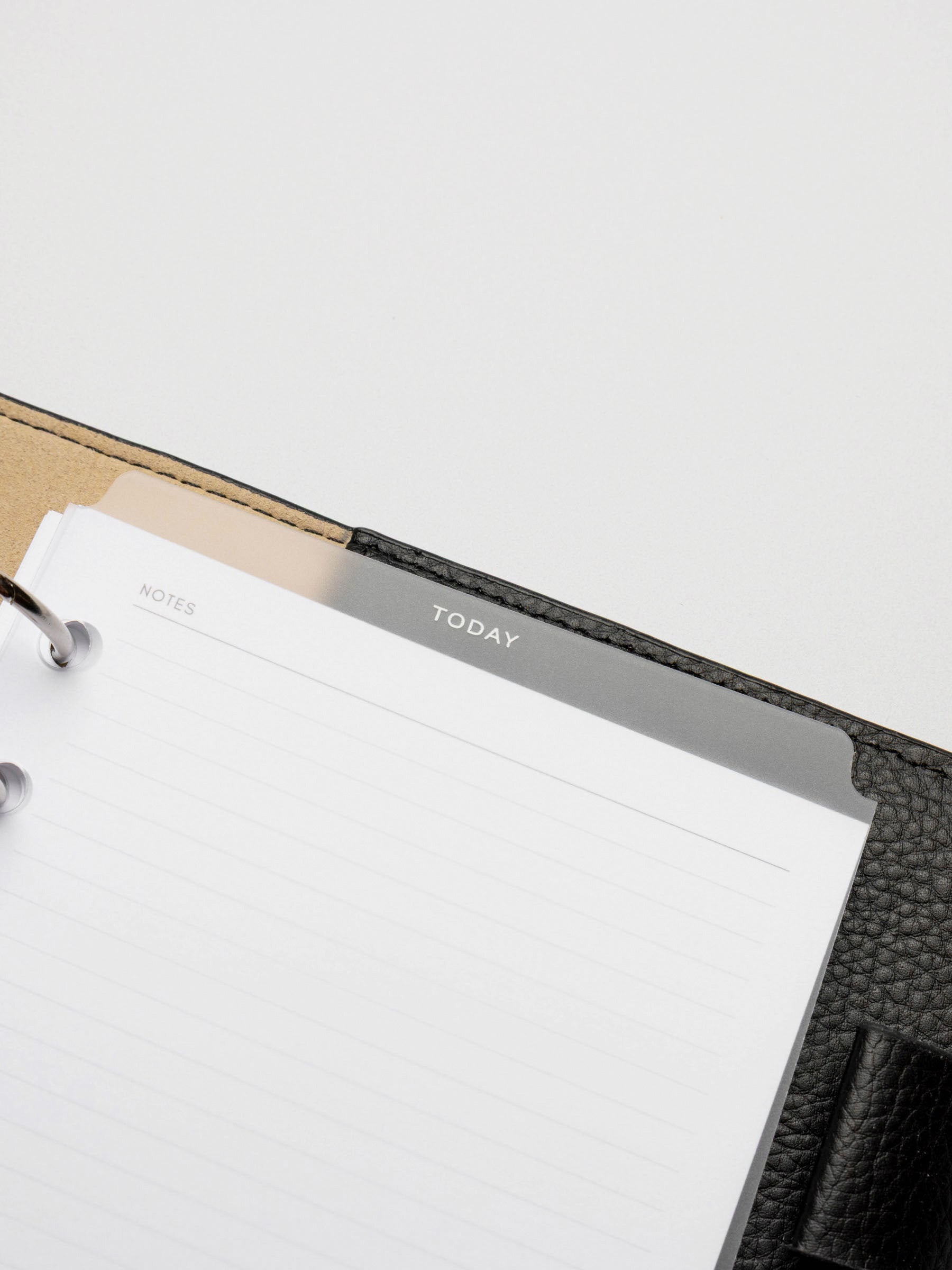 White  foil divider displayed in a black leather planner.