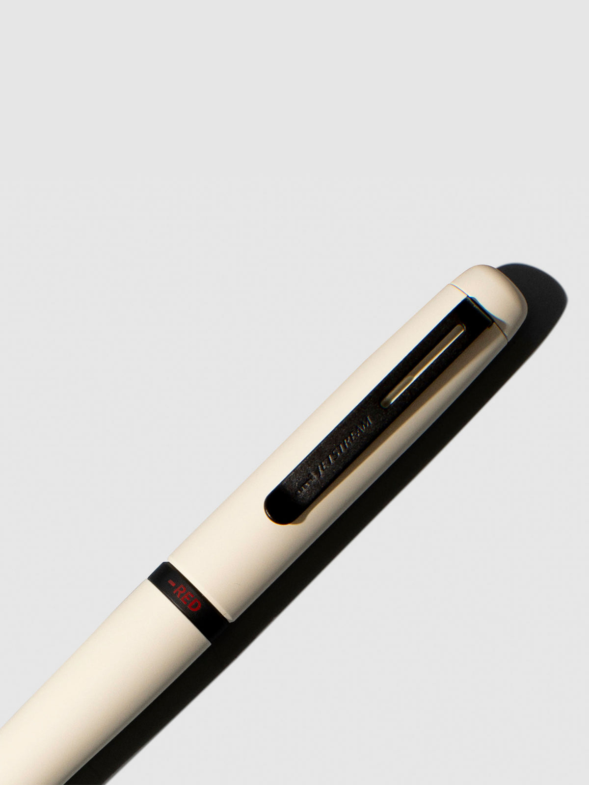 Pen shown close up, with the color selecting ring in focus. Pen ink color selected is red, pen body is Cloudy White.