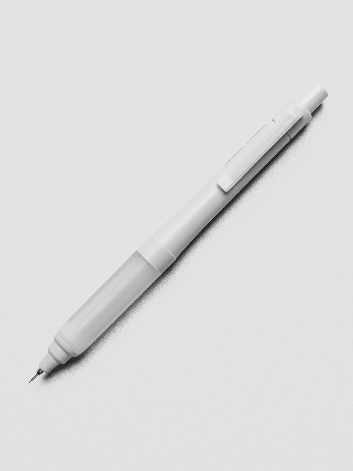 Grey mechanical pencil on a grey background.