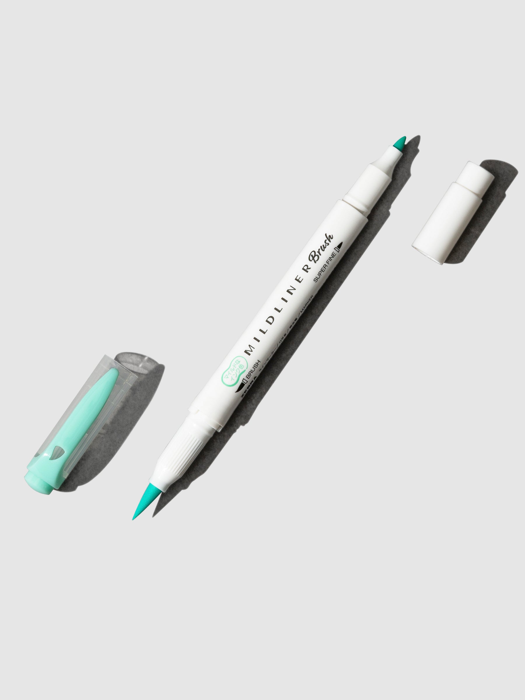 Zebra Mildliner Dual Tip Brush Pen in Blue Green displayed with caps removed from both ends. Pen is turned to the right against a neutral background.